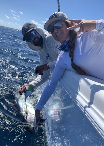 Angler displaying her prize tuna along side the boat